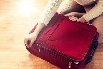 summer vacation, travel, tourism and objects concept - close up of woman packing and zipping travel bag for vacation. close up of woman packing travel bag for vacation
