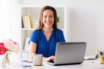 business, people and technology concept - happy smiling woman with laptop computer working at home or office. happy woman with laptop working at home or office
