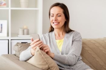 technology, communication and people concept - happy woman texting message on smartphone at home. happy woman texting message on smartphone at home