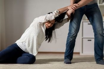 domestic violence, abuse and people concept - couple having fight and man dragging helpless woman by hair at home. unhappy woman suffering from home violence