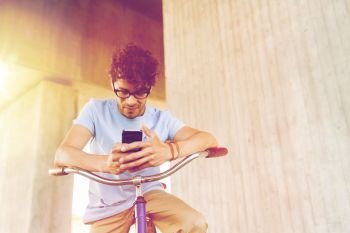 people, communication, technology, leisure and lifestyle - hipster man texting on smartphone with fixed gear bicycle on city street. man with smartphone and fixed gear bike on street