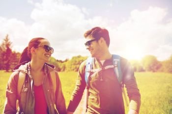 travel, hiking, backpacking, tourism and people concept - happy couple with backpacks holding hands and walking along country road outdoors. happy couple with backpacks hiking outdoors