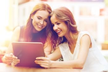 technology, lifestyle, friendship and people concept - happy young women or teenage girls with tablet pc at cafe outdoors. happy young women or teenage girls with tablet pc