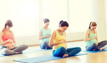 pregnancy, sport, fitness, people and healthy lifestyle concept - group of happy pregnant women exercising yoga in lotus pose in gym. happy pregnant women exercising yoga in gym