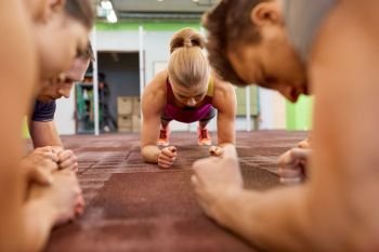 fitness, sport, exercising, training and healthy lifestyle concept - group of people doing plank exercise in gym. group of people doing plank exercise in gym