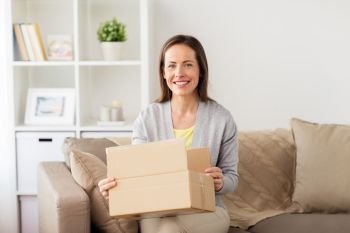 delivery, mail and people concept - smiling woman opening cardboard box at home. smiling woman opening cardboard box