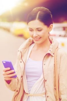 travel, business trip, people and tourism concept - smiling young woman with smartphone over taxi station or city street. smiling woman with smartphone over taxi in city