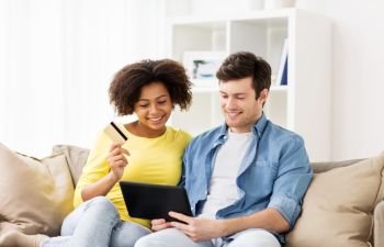 technology, online shopping and people concept - smiling happy couple couple with tablet pc computer and credit card at home. couple with tablet pc and credit card at home