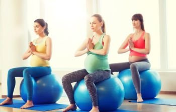 pregnancy, sport, fitness, people and healthy lifestyle concept - group of happy pregnant women exercising on ball in gym. happy pregnant women exercising on fitball in gym