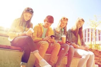 technology, internet and people concept - group of happy teenage friends with smartphone and coffee cups outdoors. teenage friends with smartphone and coffee cups
