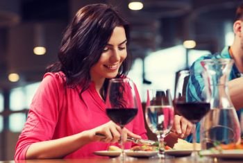 leisure, food and drinks, people and holidays concept - happy woman with friends having dinner at restaurant. happy woman having dinner at restaurant