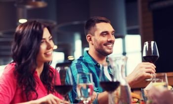 leisure, celebration, food and drinks, people and holidays concept - happy couple and friends clinking glasses of wine at restaurant. friends clinking glasses of wine at restaurant