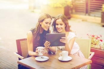 technology, lifestyle, friendship and people concept - happy young women or teenage girls with tablet pc computer drinking coffee at outdoor cafe. young women with tablet pc and coffee at cafe
