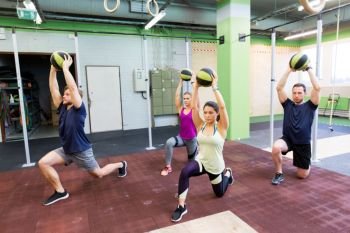 fitness, sport and exercising concept - group of people with medicine balls training in gym. group of people with medicine ball training in gym