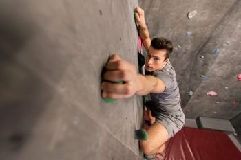 fitness, extreme sport, bouldering, people and healthy lifestyle concept - young man exercising at indoor climbing gym. young man exercising at indoor climbing gym