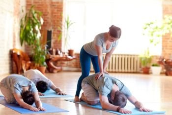 fitness, sport and healthy lifestyle concept - group of people with personal trainer doing yoga hare pose on mats in gym or studio. group of people doing yoga exercises at studio