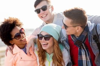 people, friendship and teenage concept - group of happy friends in sunglasses having fun and laughing outdoors. happy teenage friends in shades laughing outdoors