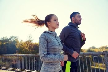 fitness, sport, people and jogging concept - happy couple running outdoors. happy couple running outdoors