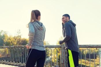 fitness, sport, people and lifestyle concept - happy couple with earphones running outdoors. happy couple with earphones running outdoors