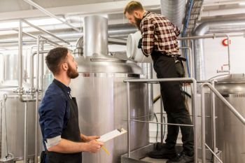manufacture, business and people concept - men working at craft brewery or beer plant. men working at craft brewery or beer plant