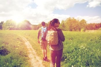 travel, hiking, backpacking, tourism and people concept - happy couple with backpacks walking along country road. happy couple with backpacks hiking outdoors