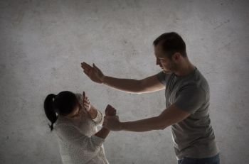 domestic violence, people and abuse concept - couple having fight and man beating woman over gray concrete background. couple having fight and man beating woman