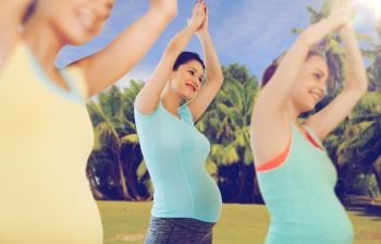 pregnancy, sport, fitness, people and healthy lifestyle concept - group of happy pregnant women exercising in gym. happy pregnant women exercising outdoors