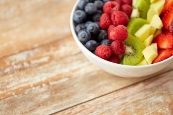 healthy eating and food concept - close up of fruits and berries in bowl on wooden table. close up of fruits and berries in bowl