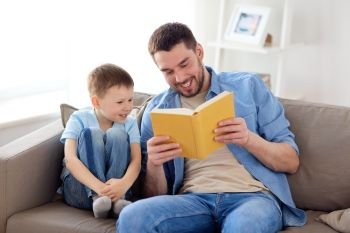 family, childhood, fatherhood, leisure and people concept - portrait of happy smiling father and little son reading book on sofa at home. happy father and son reading book sofa at home