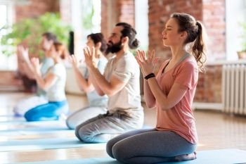 fitness, yoga and healthy lifestyle concept - group of people doing lotus seal gesture and meditating in seated pose at studio. group of people meditating at yoga studio