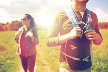 travel, hiking, backpacking, tourism and people concept - close up of couple with backpacks walking along country road. close up of couple with backpacks hiking outdoors