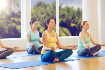 pregnancy, sport, fitness, people and healthy lifestyle concept - group of happy pregnant women exercising yoga and meditating in lotus pose in gym. happy pregnant women exercising yoga in gym