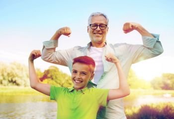 family, generation, power and people concept - happy grandfather and grandson showing muscles. happy grandfather and grandson showing muscles