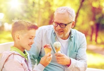 family, generation, communication and people concept - happy grandfather and grandson eating ice cream at summer park. old man and boy eating ice cream at summer park