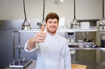cooking, profession and people concept - happy male chef cook at restaurant kitchen showing thumbs up. happy chef at restaurant kitchen showing thumbs up