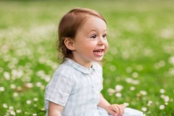 childhood, leisure and people concept - happy baby girl on green summer field. happy baby girl on green summer field
