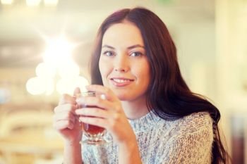 leisure, drinks, people and lifestyle concept - smiling young woman drinking tea at cafe. smiling young woman drinking tea at cafe