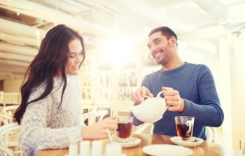 people, communication and dating concept - happy couple drinking tea at cafe or restaurant. happy couple drinking tea at cafe