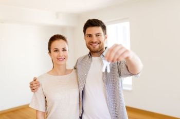 mortgage, people and real estate concept - happy couple with keys at empty room of new home. happy couple with keys of new home