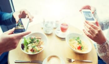 people, technology, eating and dating concept - close up of couple with smartphones picturing food at cafe or restaurant. close up of couple picturing food by smartphone