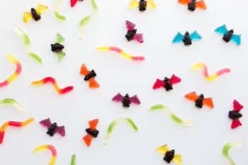 halloween, junk food and confectionery concept concept - multicolored gummy worms and jelly bet candies over white background. gummy worms and bet candies for halloween party
