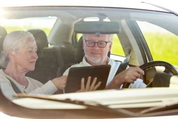 road trip, travel and old people concept - happy senior couple with tablet pc computer driving in car. happy senior couple with tablet pc driving in car