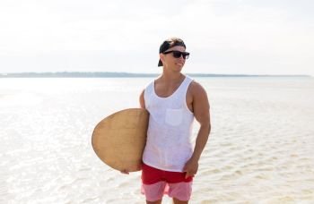 skimboarding, water sport and people concept - happy smiling young man with skimboard on summer beach. happy young man with skimboard on summer beach