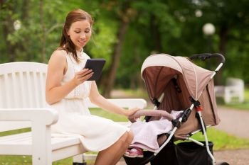 motherhood, technology and people concept - happy mother with tablet pc computer or e-book reader and baby girl stroller at summer park. happy mother with tablet pc and stroller at park