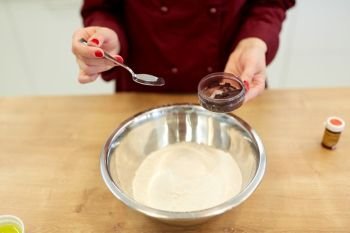 cooking, baking and people concept - chef hands with flour in bowl and food color additive making batter or dough. chef hands adding food color into bowl with flour