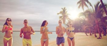 summer holidays and people concept - group of smiling friends wearing swimwear and sunglasses running over exotic tropical beach with palm trees background. smiling friends in sunglasses running on beach