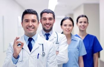 clinic, profession, people, health care and medicine concept - group of happy medics or doctors at hospital corridor showing ok hand sign. group of happy medics or doctors at hospital