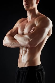 sport, bodybuilding, fitness and people concept - close up of young man or bodybuilder with bare torso over black background. close up of man or bodybuilder with bare torso