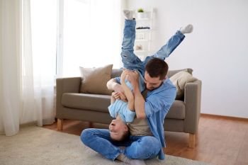 family, childhood, fatherhood, leisure and people concept - happy father and little son playing and having fun on sofa at home. father with son playing and having fun at home