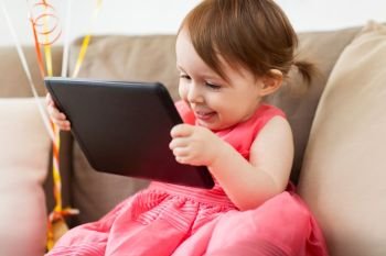 childhood, people and technology concept - happy baby girl with tablet pc computer at home. baby girl with tablet pc at home